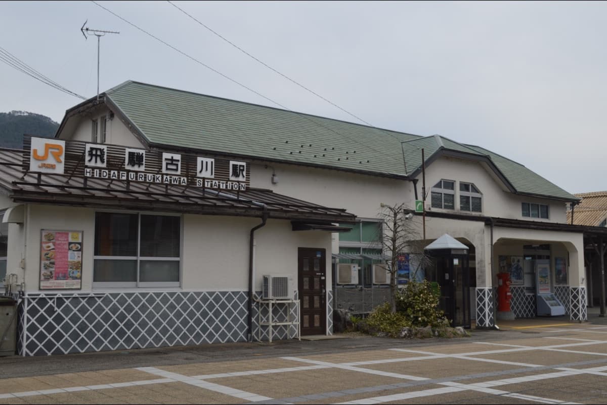 JR Hida-Furukawa Station exterior with bilingual signage and a green tiled roof