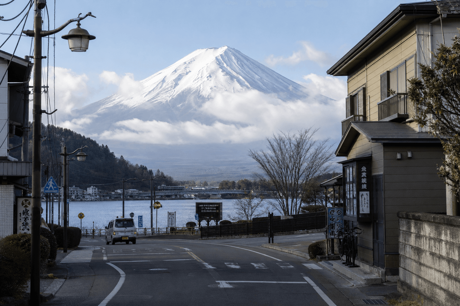 Mount Fuji rising beyond a lakeside town edge with local rooftops in the foreground
