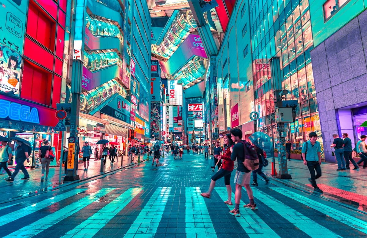 People walking along a brightly lit Tokyo street at night