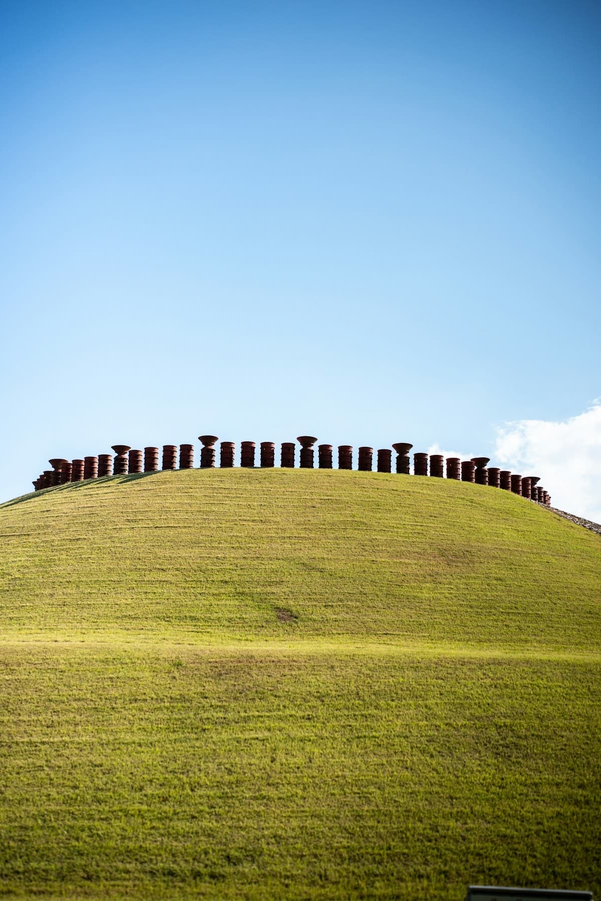 Terracotta sculptures line a grassy hillside under open sky — calm museum-garden atmosphere above the valley.
