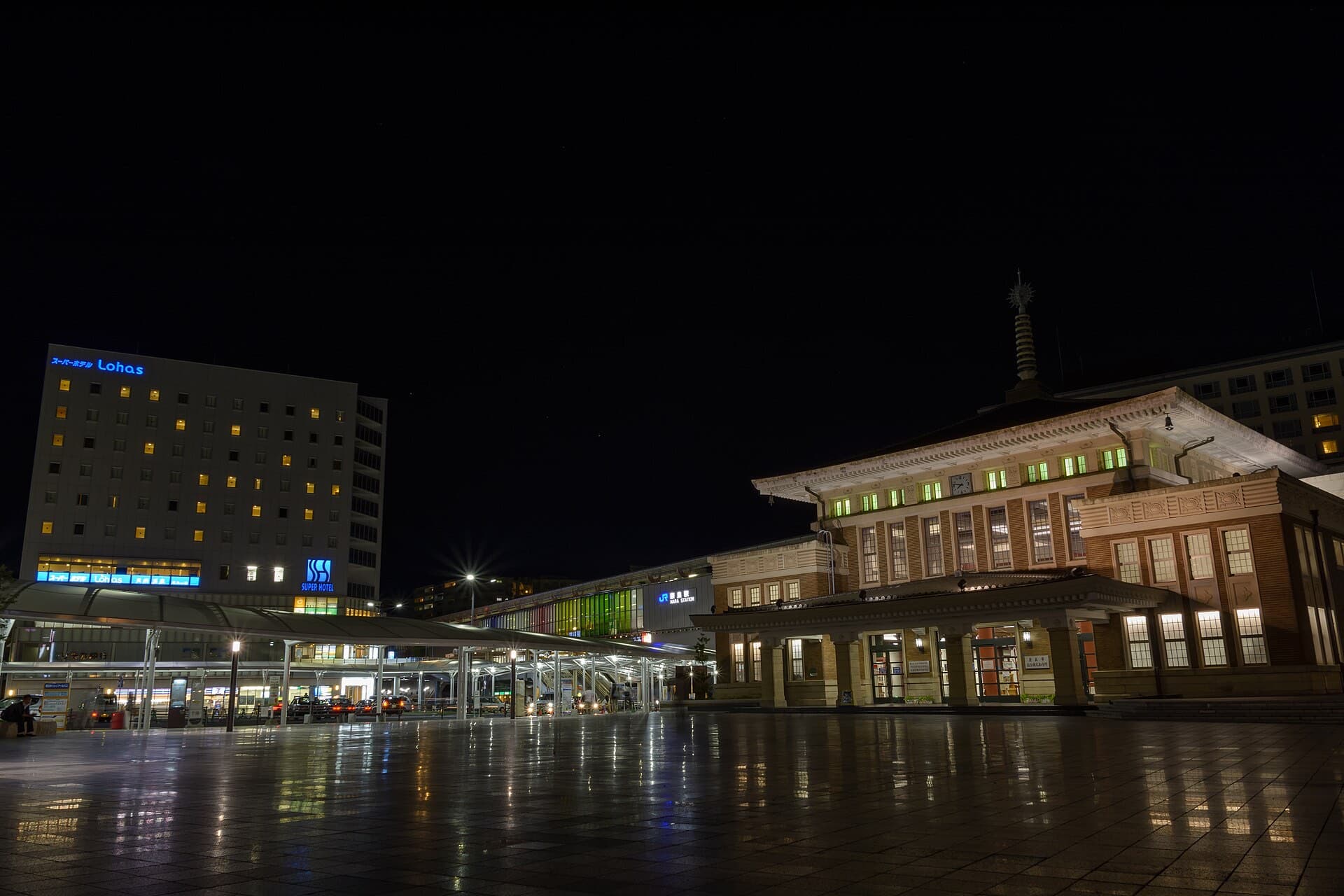 JR Nara Station at night, showing the preserved pagoda-roofed 1934 station building illuminated beside the modern station entrance and plaza.