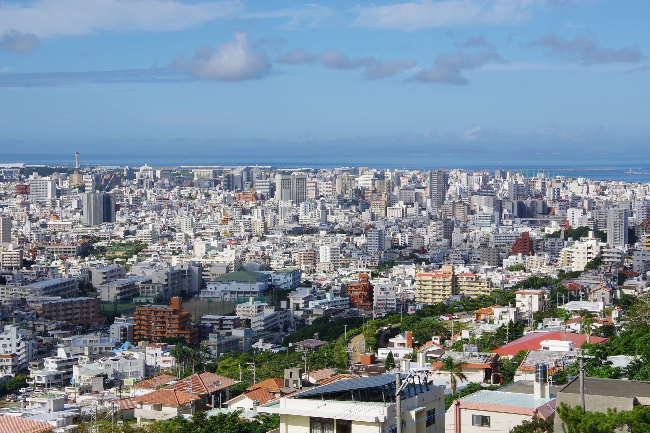 An elevated view of central Naha's dense city buildings extending to the coastline.
