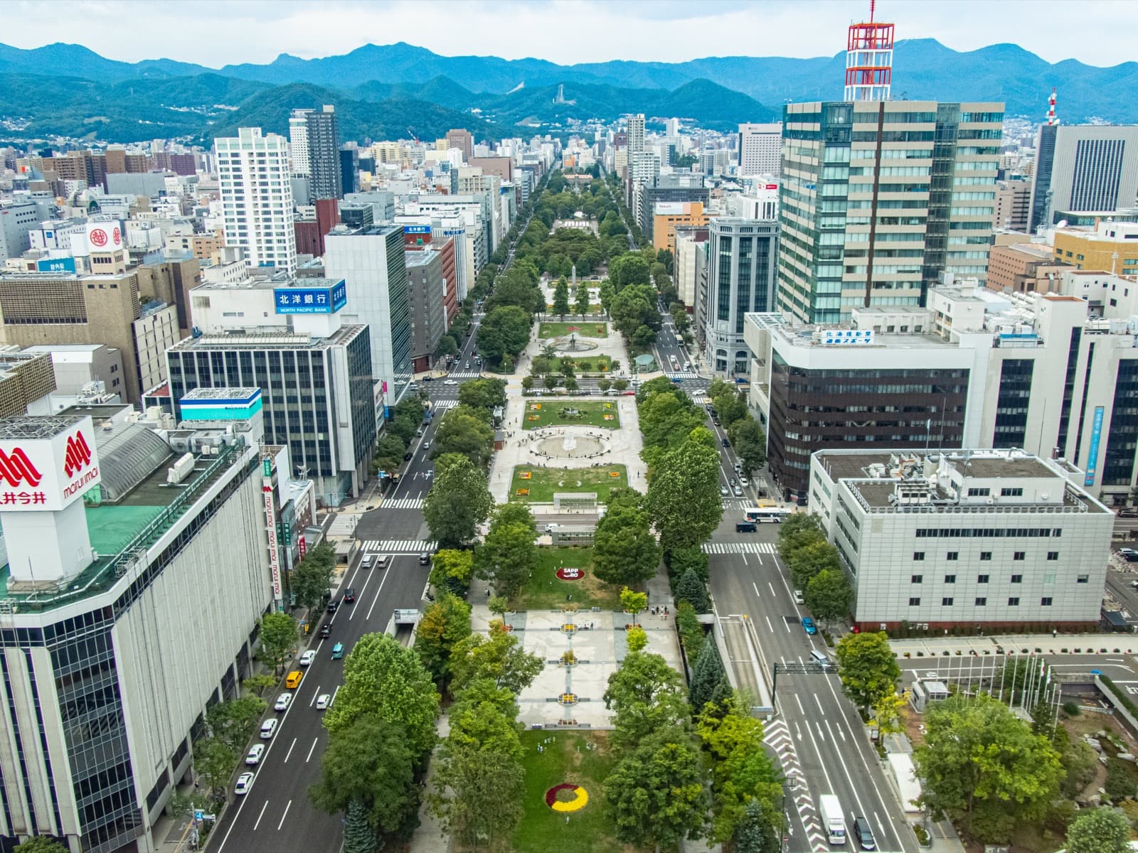An aerial view of Odori Park's green belt running through central Sapporo, flanked by city streets and buildings.