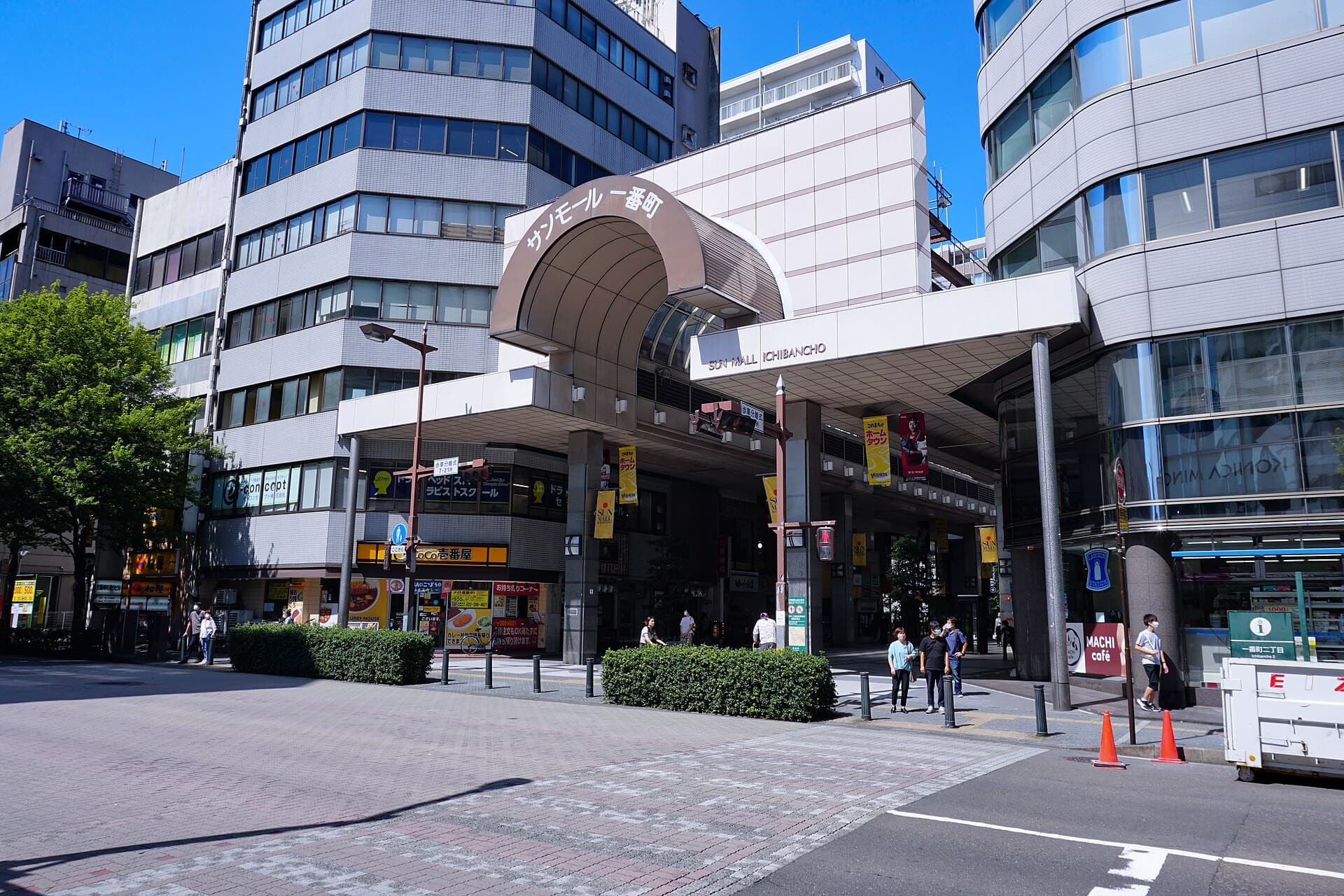 The entrance to Sun Mall Ichibancho covered shopping arcade in Sendai, with its arched roof and pedestrians on a sunny day.